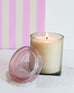 joli jar candle lit with a pink striped backdrop