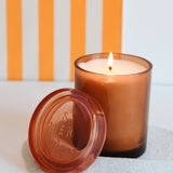 joli jar candle lit with a orange striped backdrop