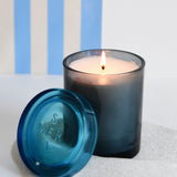 joli jar candle lit with a blue striped backdrop