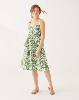 female wearing white and green floral A-line linen sundress with self-belt on white background