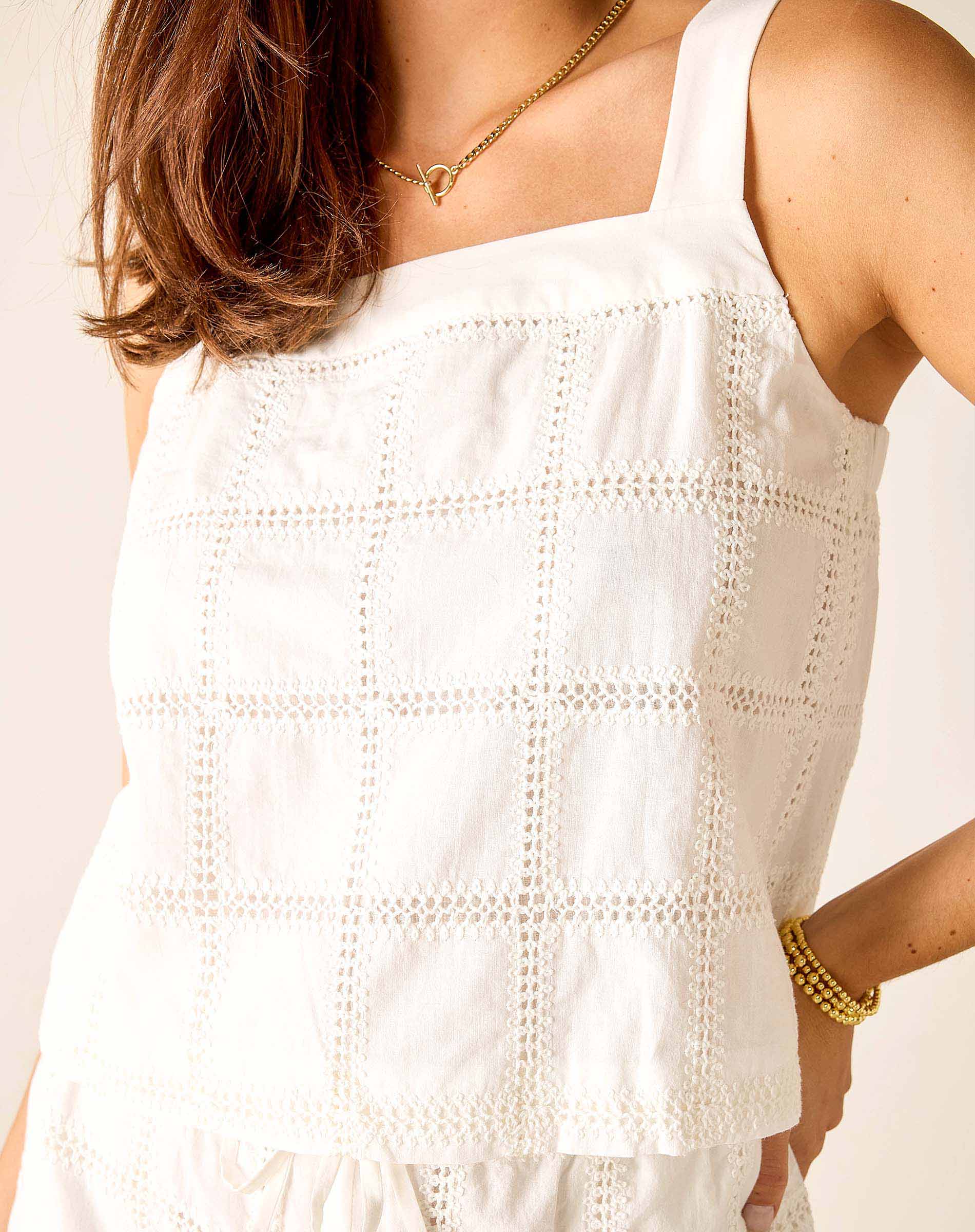 White sleeveless top worn by a person on a plain background