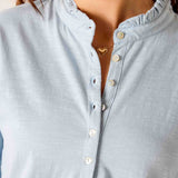 Light blue button-up shirt worn by a person with a neutral background
