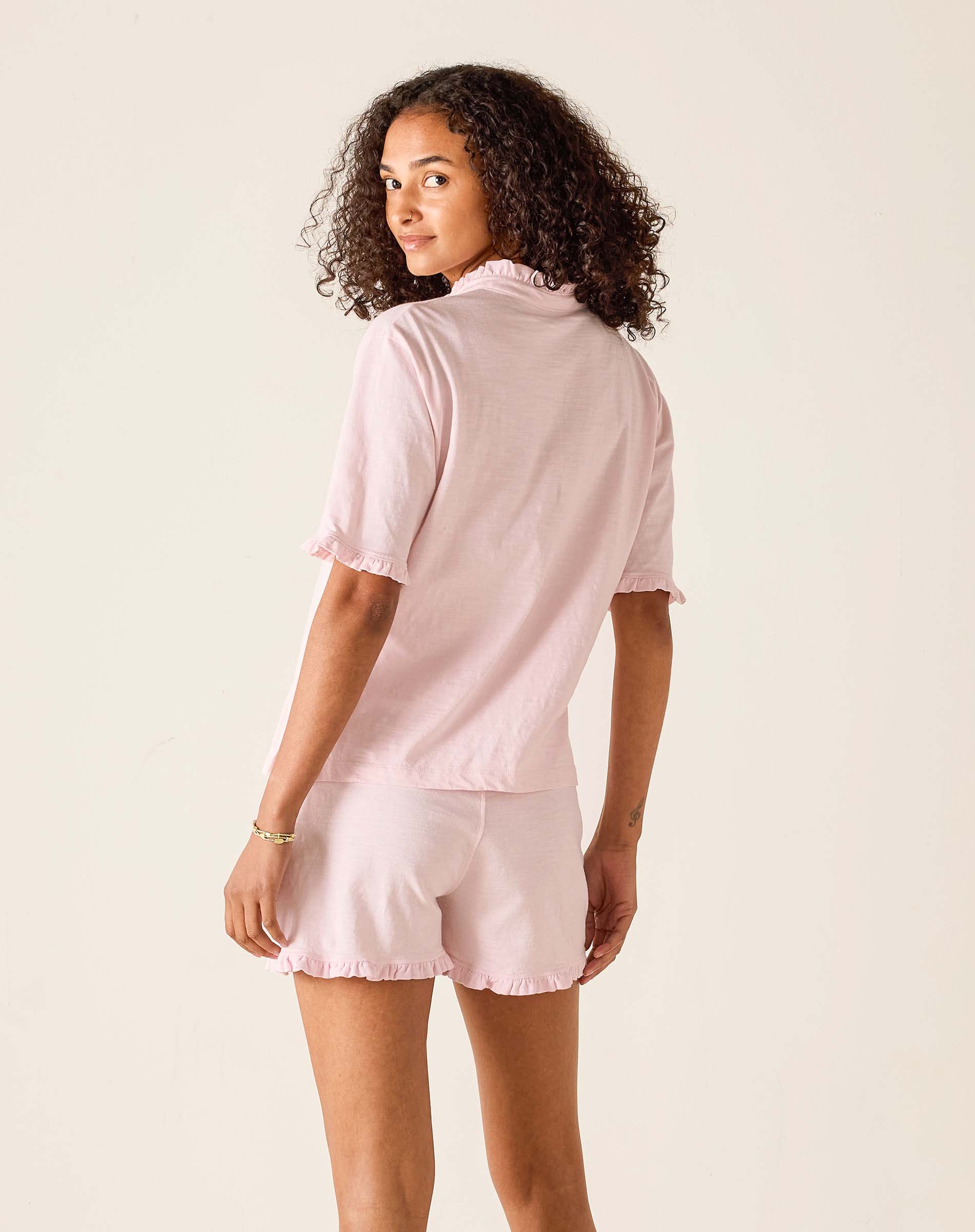 Woman wearing a light pink pajama set on a plain background