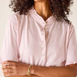 Woman wearing a light pink button-up shirt with a neutral background
