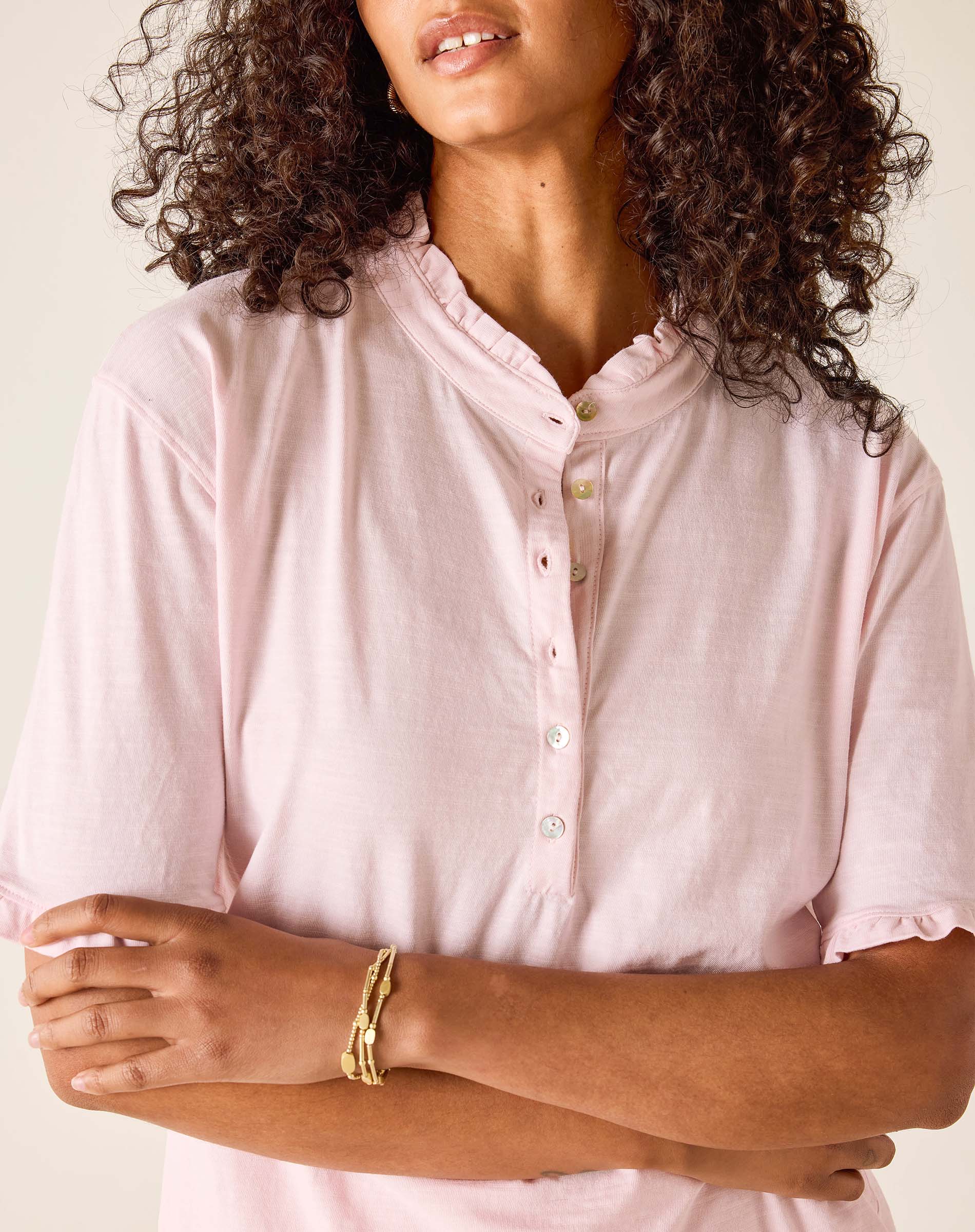 Woman wearing a light pink button-up shirt with a neutral background