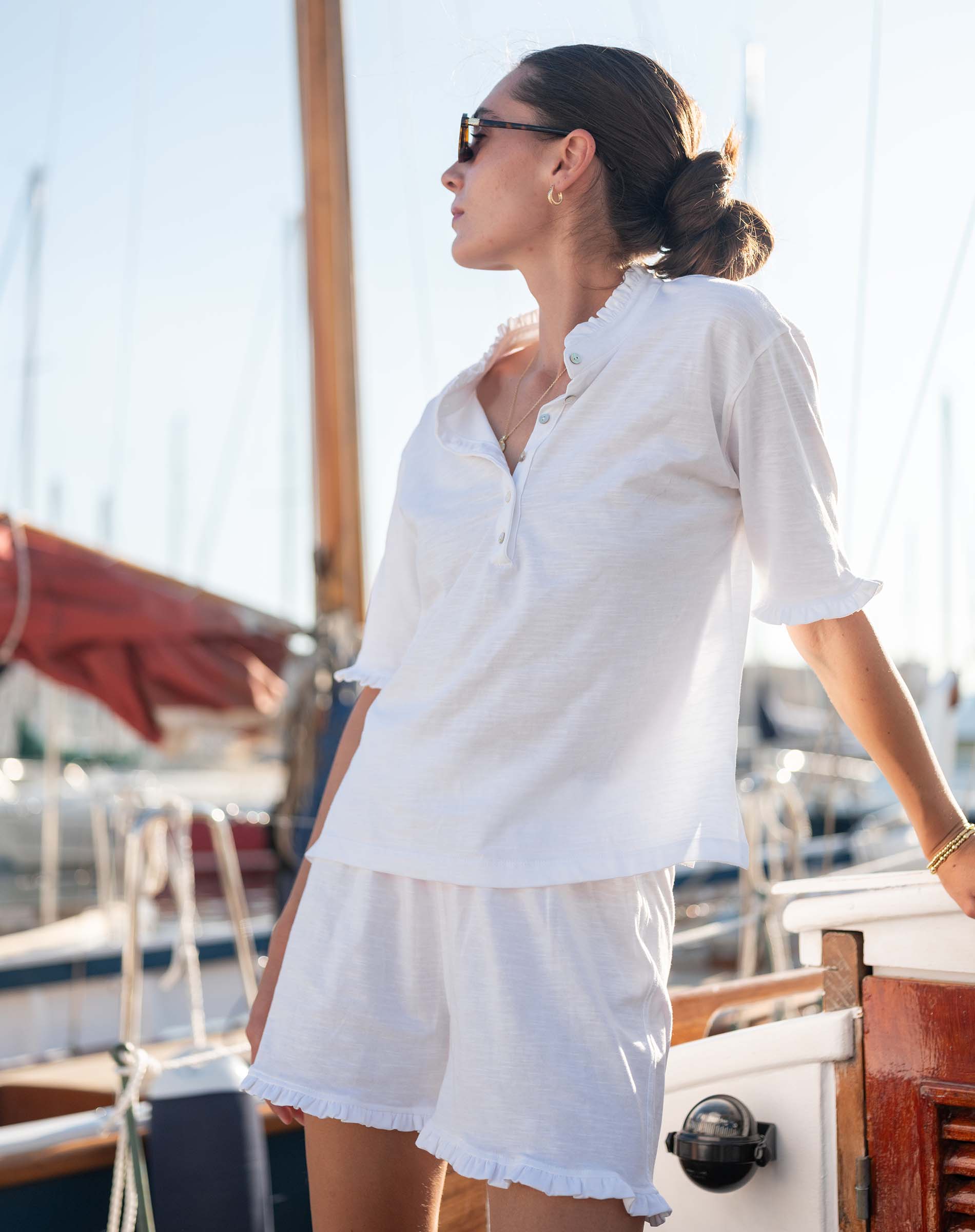 Woman in a white outfit standing on a boat with a blurred background