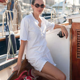 Woman in a white outfit sitting on a boat with a marina background