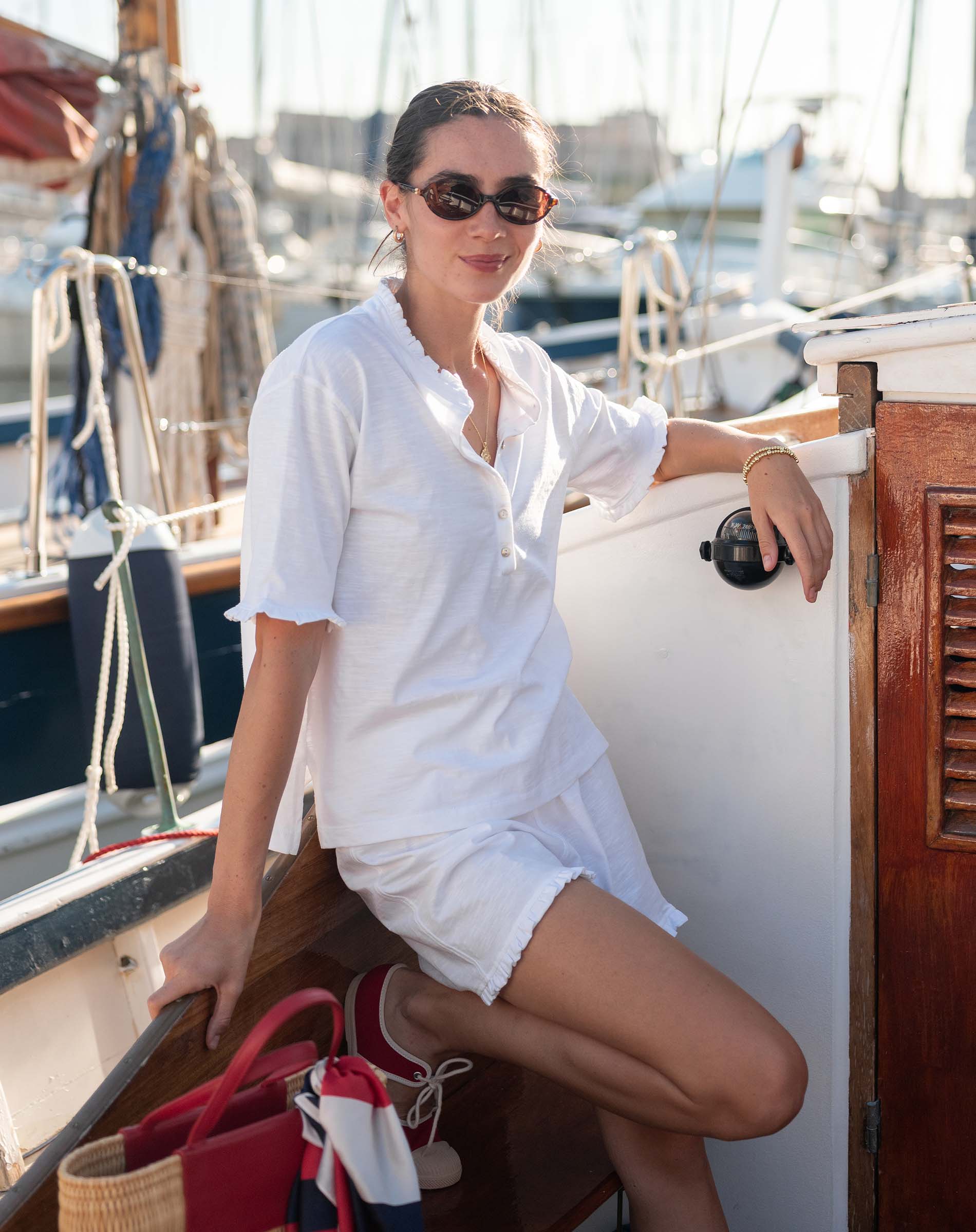 Woman in a white outfit sitting on a boat with a marina background