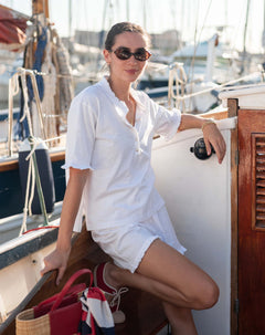 Woman in a white outfit sitting on a boat with a marina background
