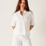 Woman wearing a white shirt and shorts on a plain background
