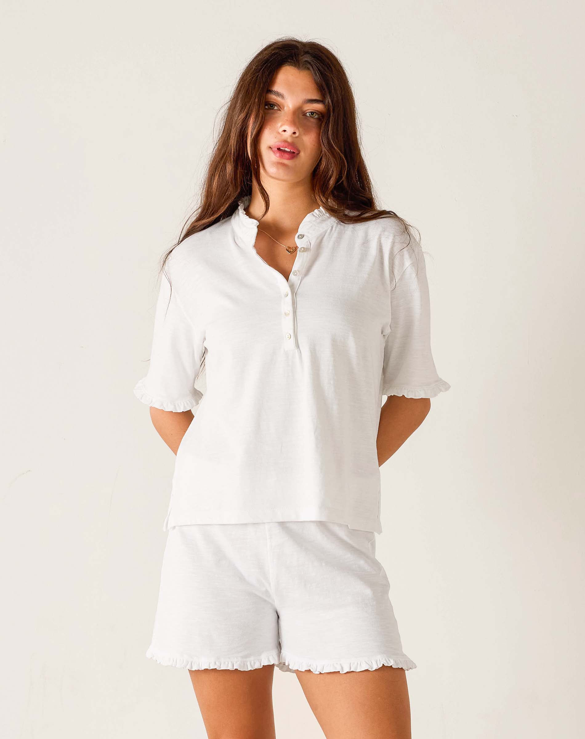 Woman wearing a white shirt and shorts on a plain background