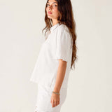 Woman wearing a white shirt and shorts on a plain background