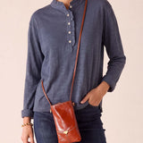 MERSEA ladies' travel-ready dusty blue long sleeve ruffle henley top with a buttoned placket and denim pants.