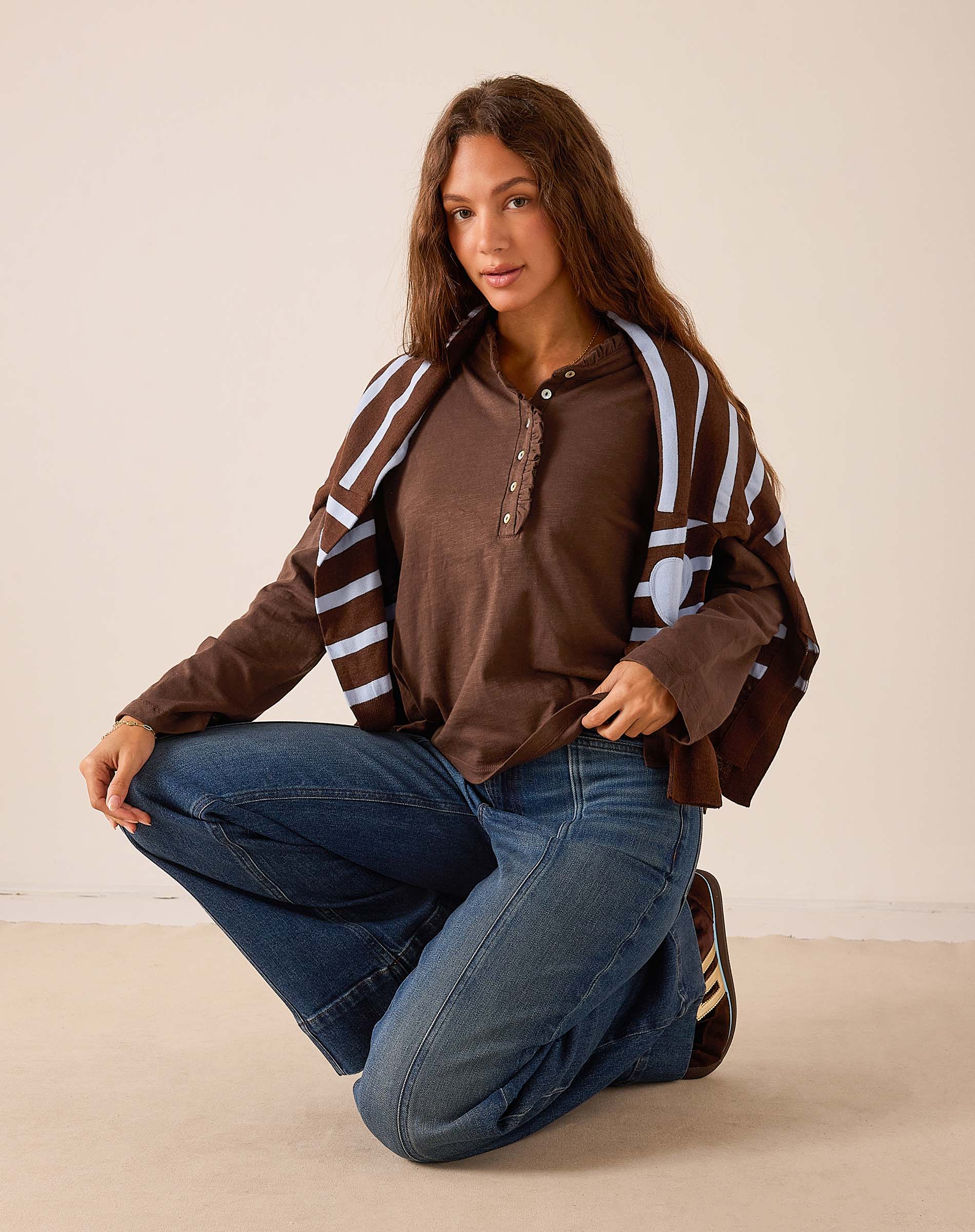 Women's travel-friendly espresso brown long-sleeved Henley top featuring ruffle details and a buttoned neckline.