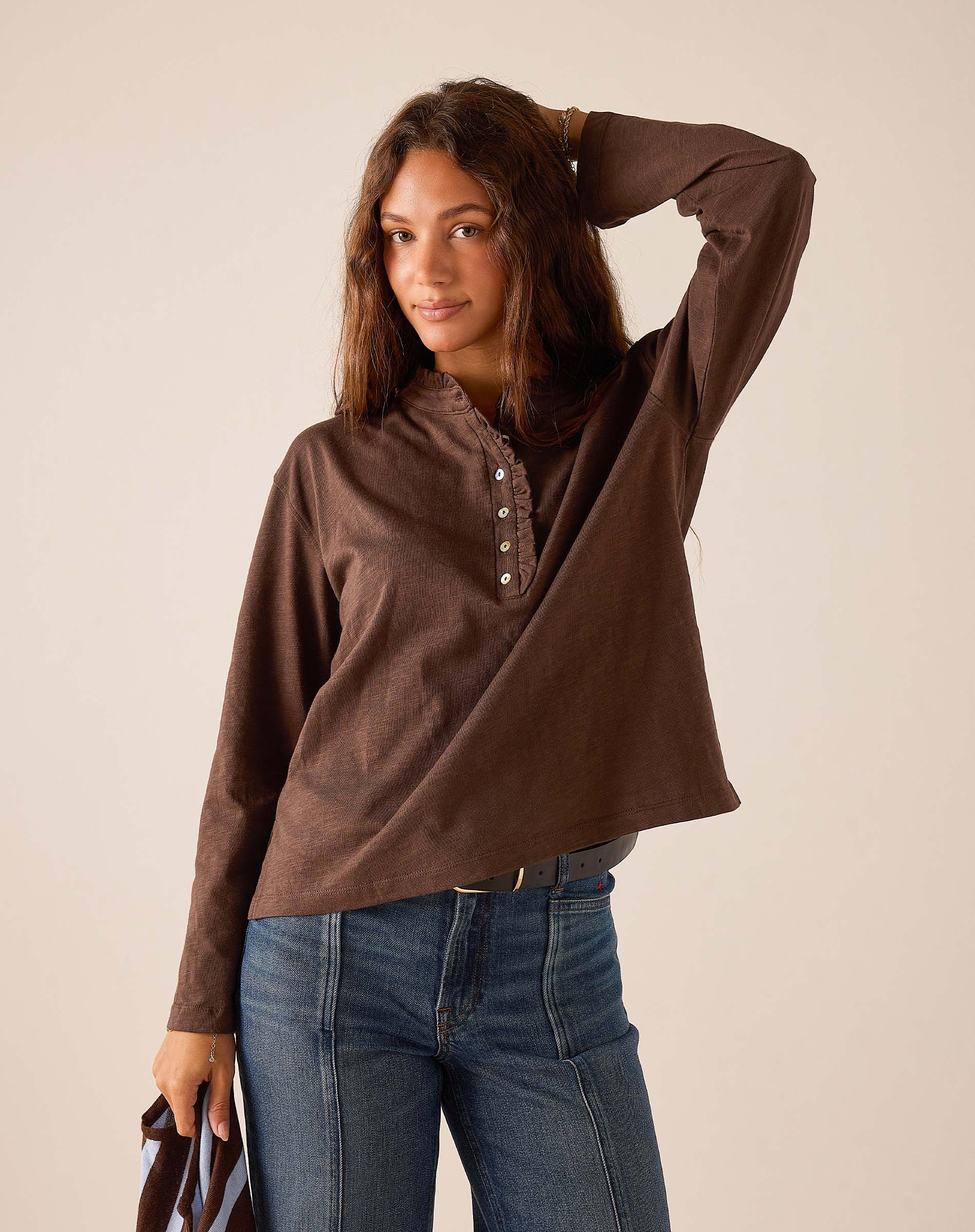 Espresso brown long-sleeved knit Henley top with buttoned ruffle detail.
