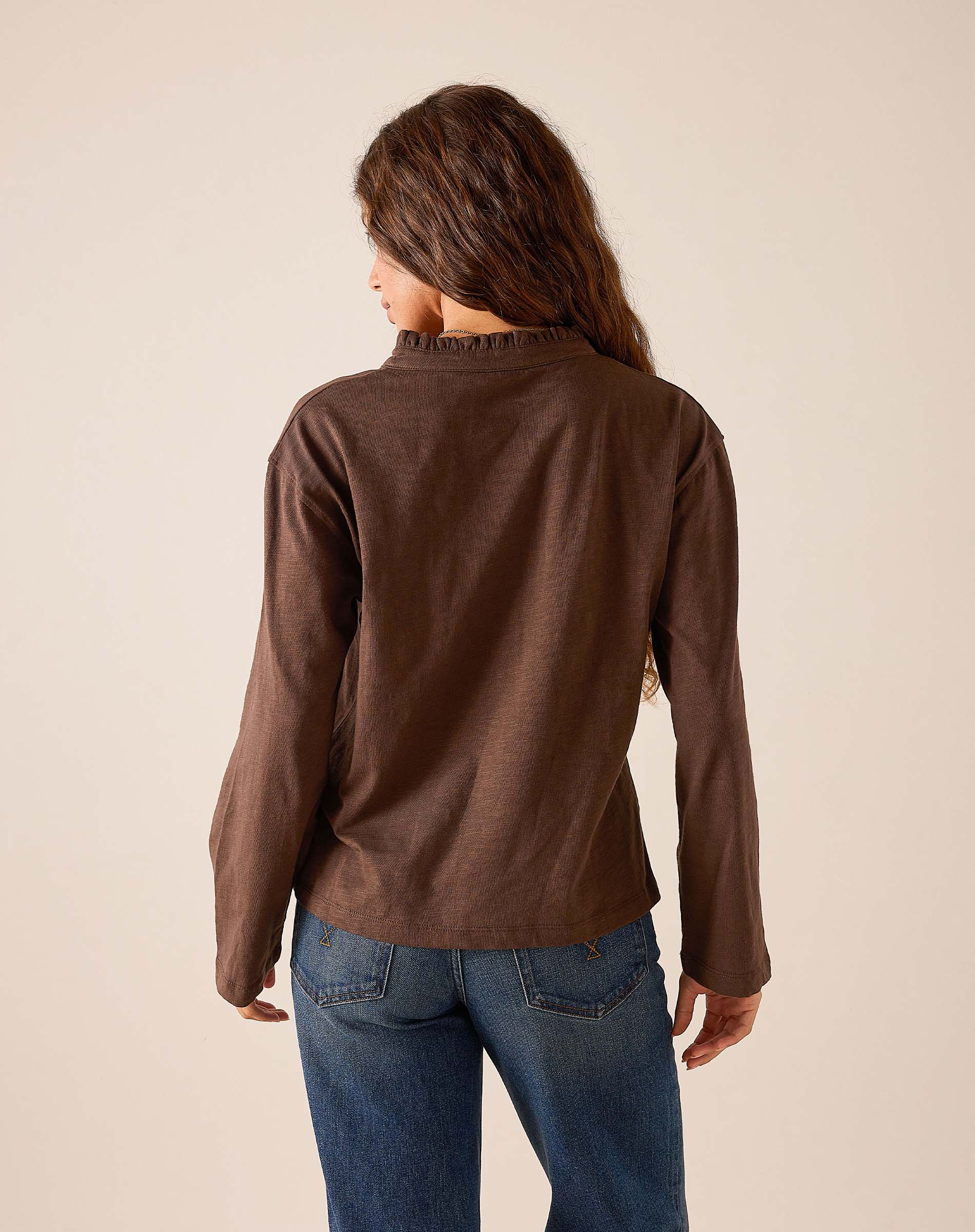 Back view of women's travel-friendly espresso brown long-sleeve ruffle henley top