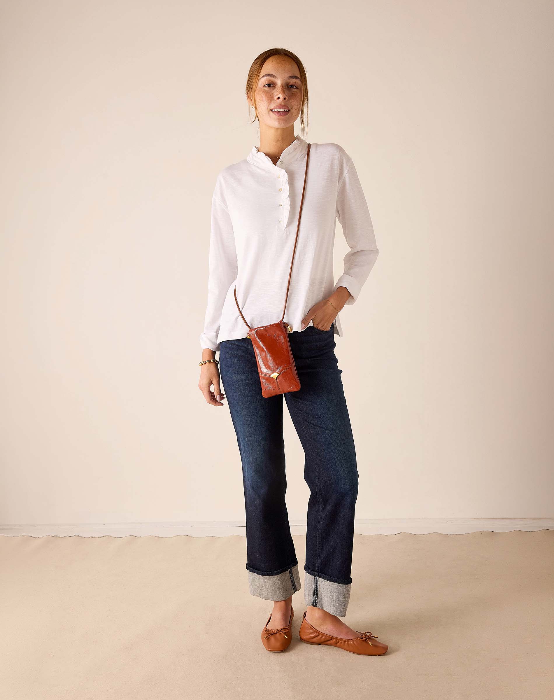 MERSEA ladies' travel-ready white long-sleeve ruffle henley top with a buttoned neck.