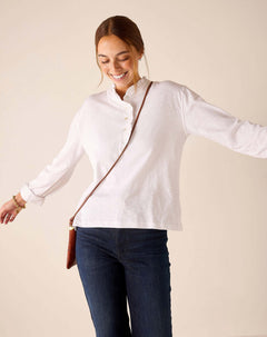 White long-sleeve ruffle henley top with a buttoned collar and textured fabric.
