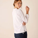 White long-sleeve ruffle henley top worn over dark wash denim jeans.