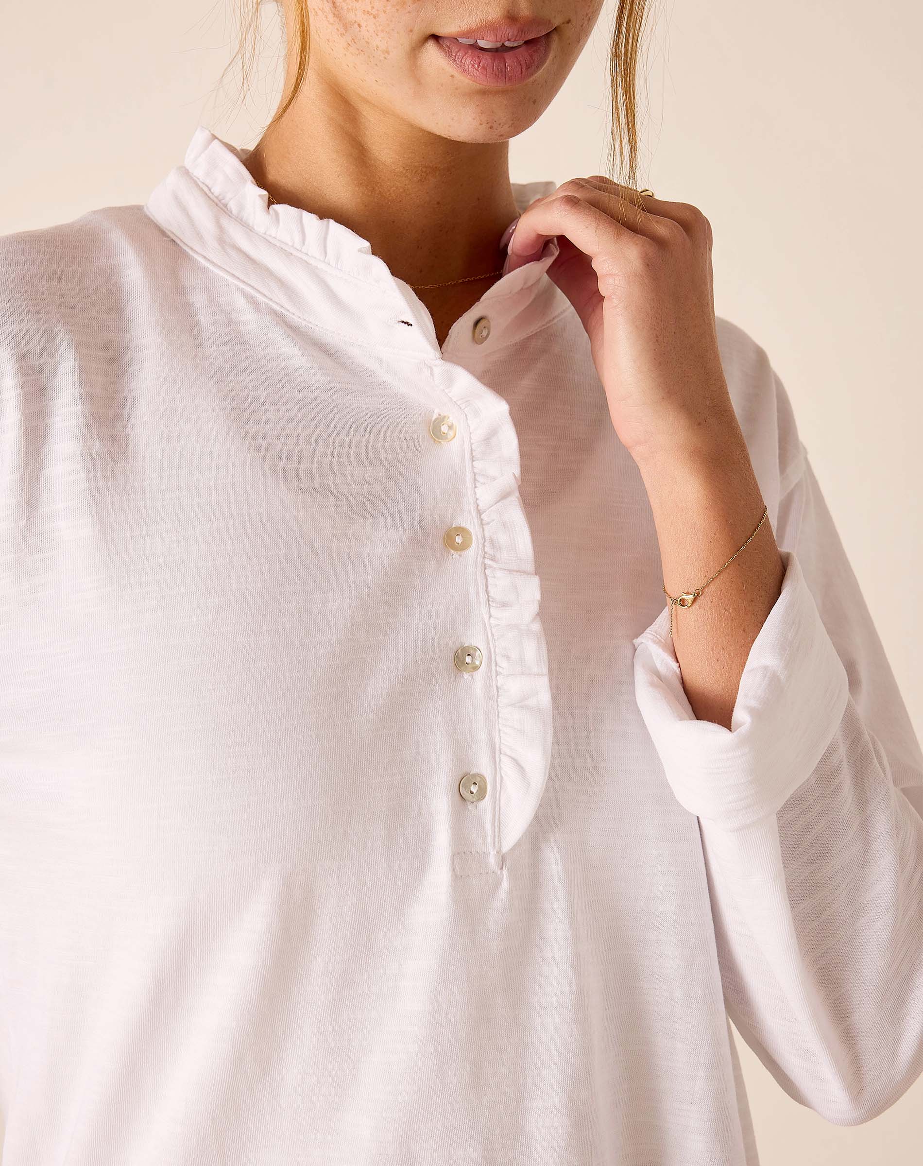 White long-sleeve ruffle Henley top with button front and gathered neck detail.