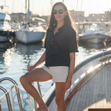 Woman on a sailboat in a marina with yachts in the background