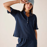 Woman wearing a navy blue outfit with a matching cap against a beige background