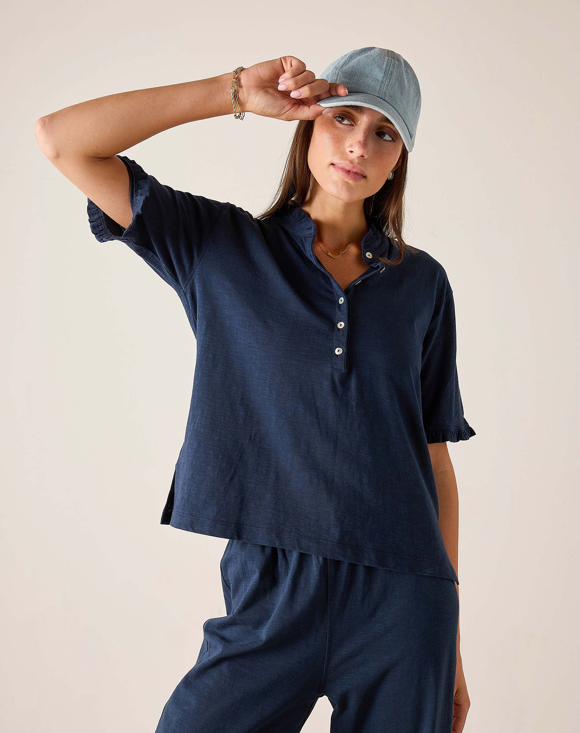 Woman wearing a navy blue outfit with a matching cap against a beige background