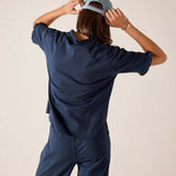 Person wearing a navy blue outfit with a cap on a beige background