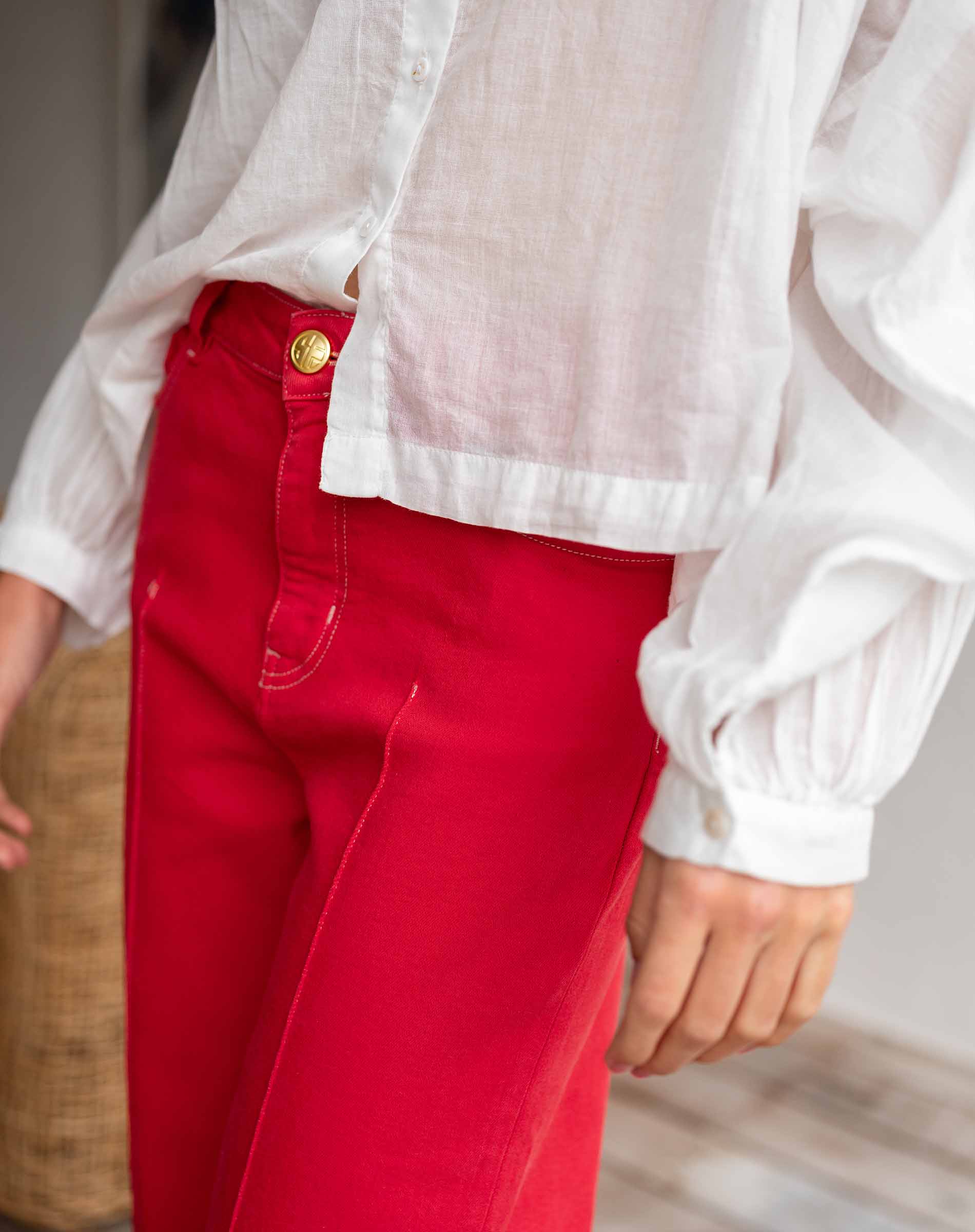 Person wearing a white shirt and red pants with a blurred background