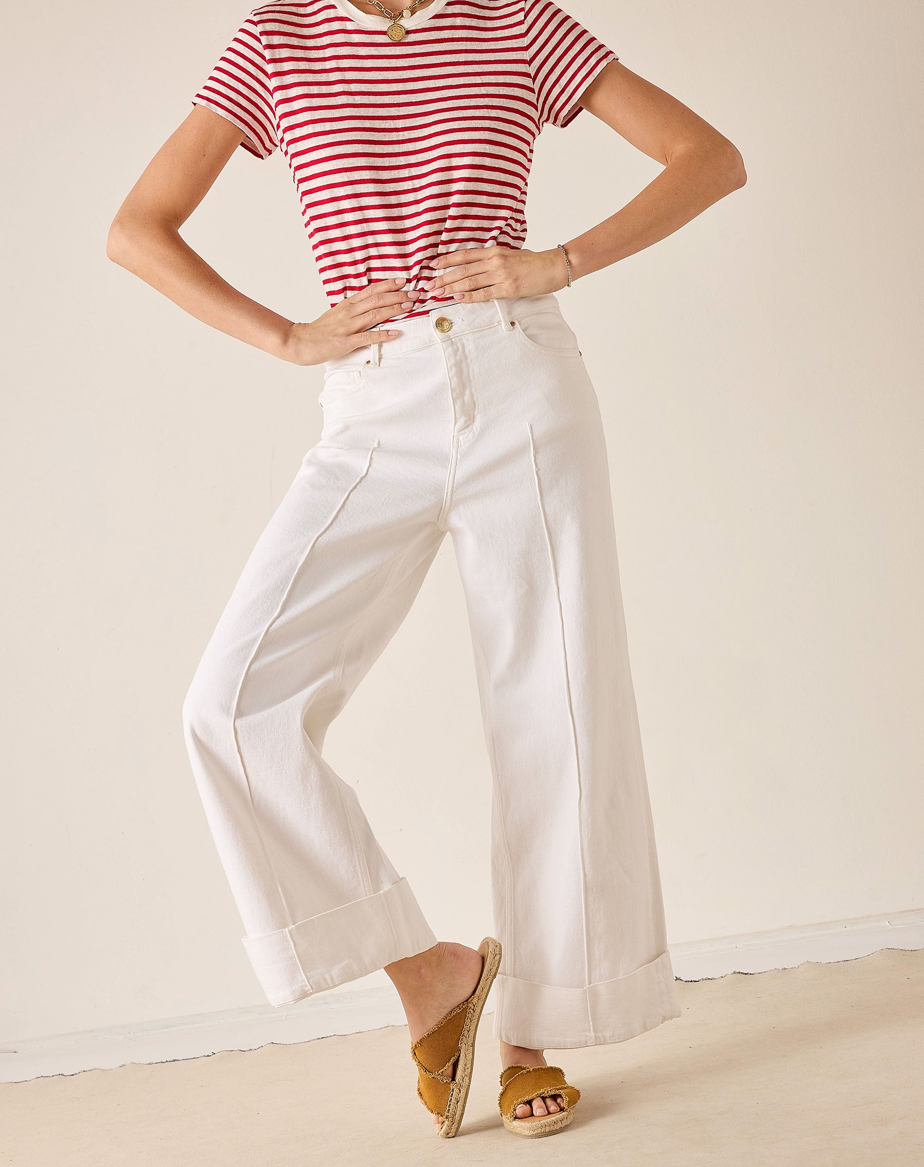 Person wearing a red and white striped shirt and white pants on a plain background