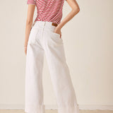 Person wearing a red and white striped shirt and white wide-leg pants against a plain background