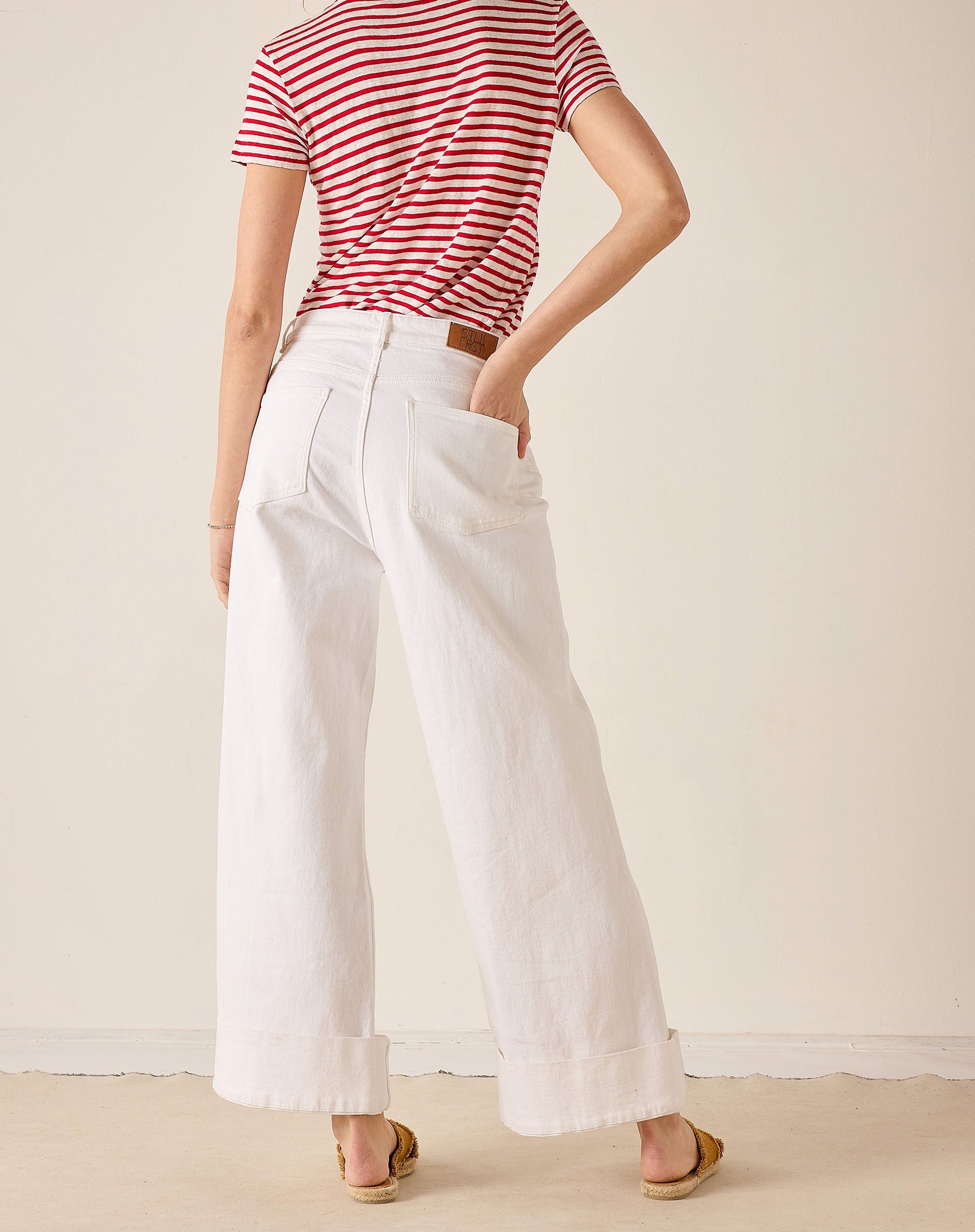 Person wearing a red and white striped shirt and white wide-leg pants against a plain background