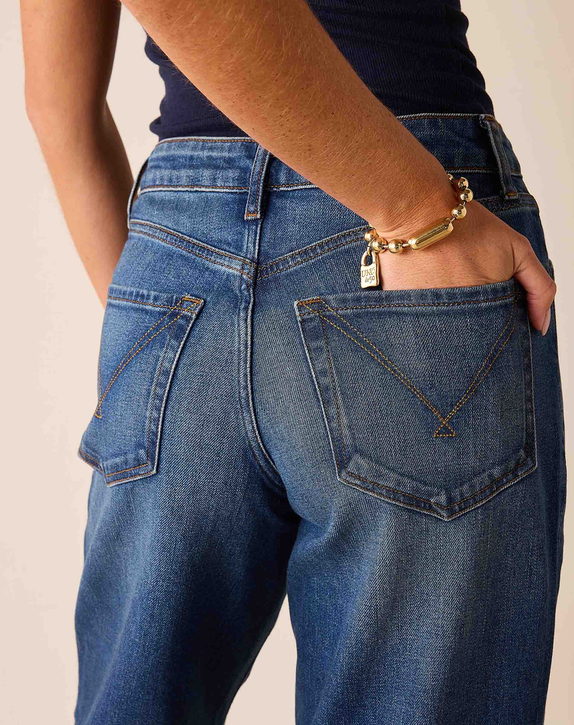 Deep pacific blue wide-leg jeans with gold-tone stitching and a metallic chain detail on the back pocket