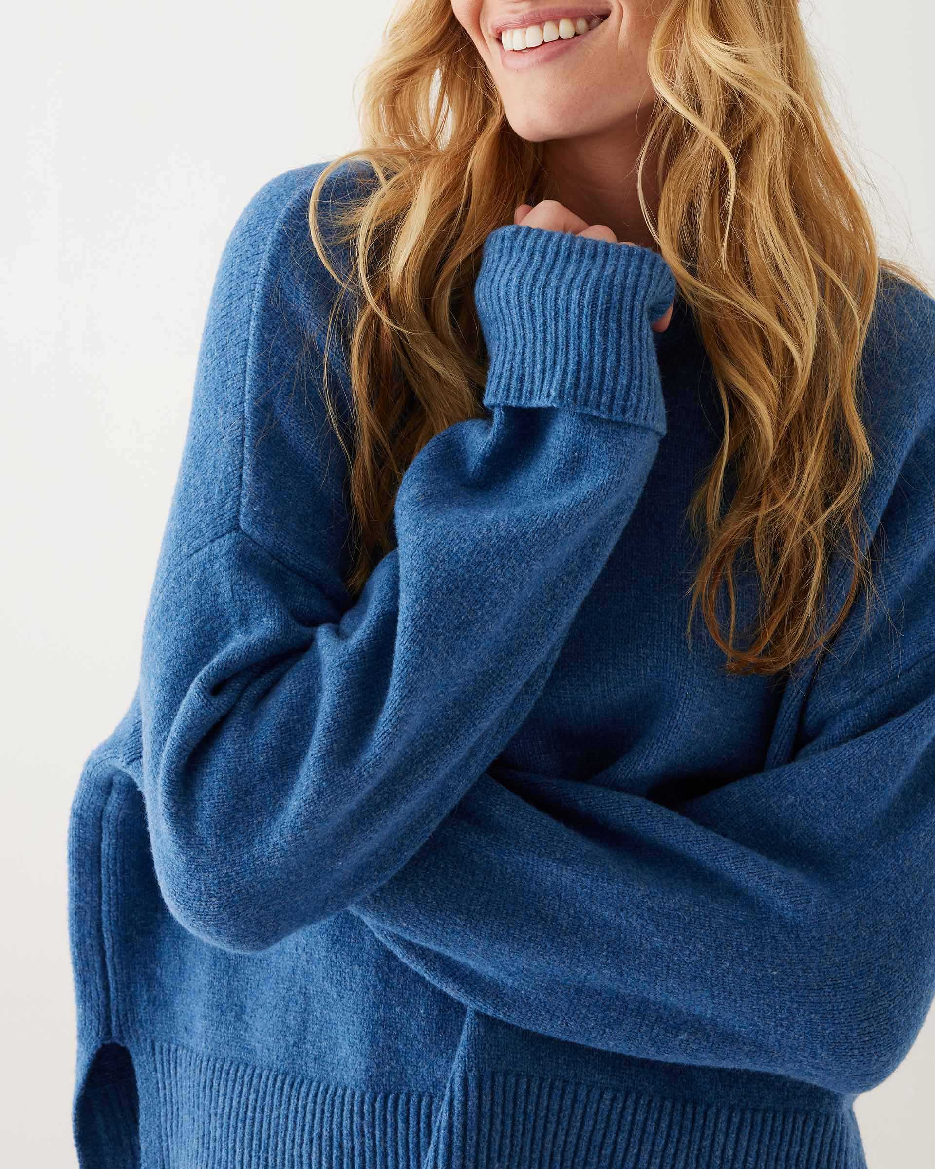 closeup of female wearing denim blue crewneck sweater standing in front of a white background