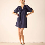 Woman wearing a navy blue dress with a plain background