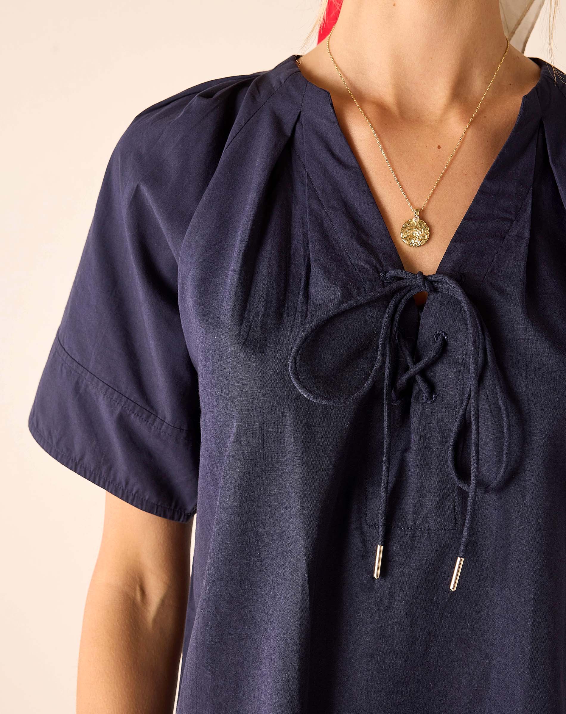 Navy blue blouse with tied sleeves and neckline on a beige background