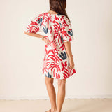 Woman wearing a red and white patterned dress against a plain background