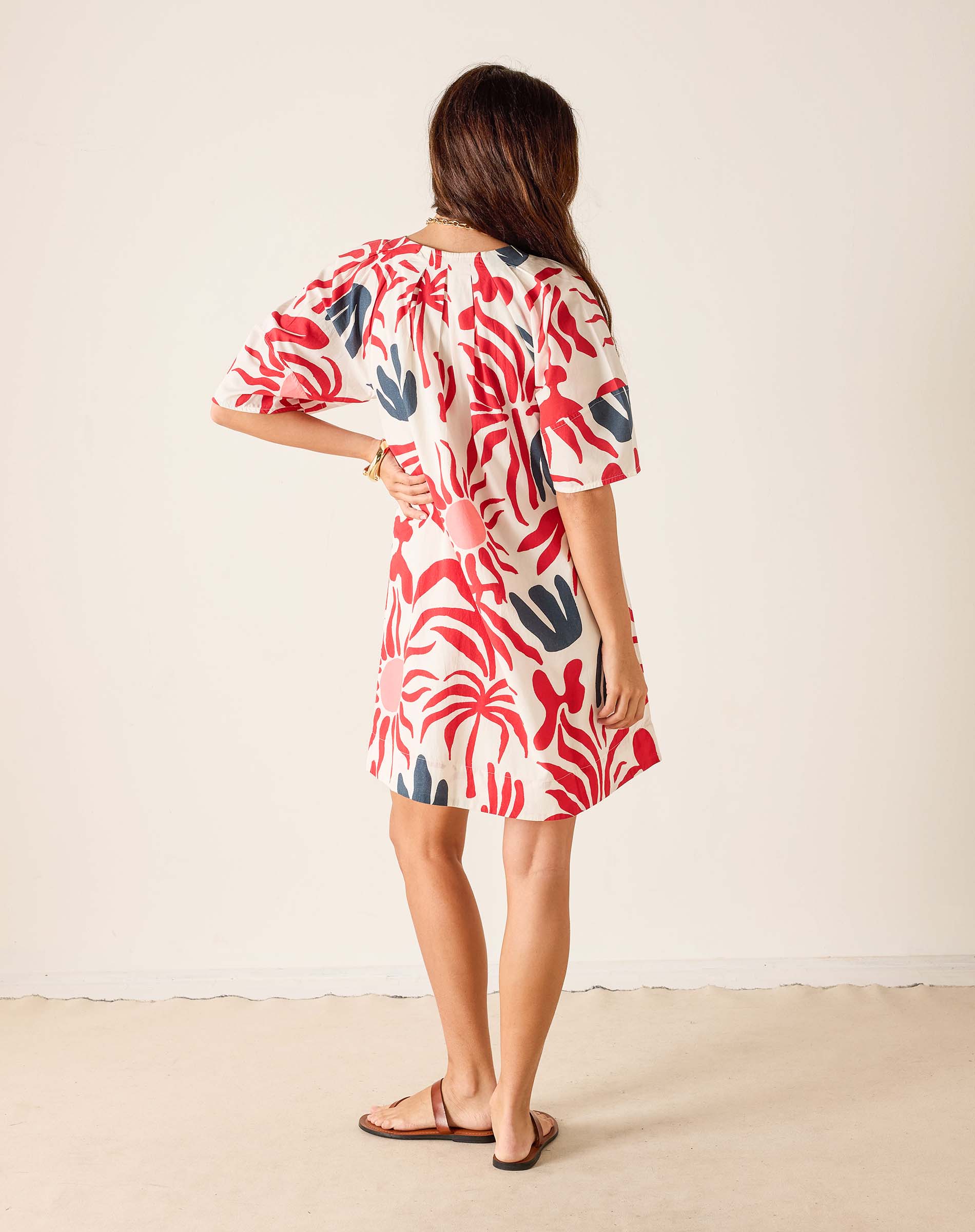 Woman wearing a red and white patterned dress against a plain background