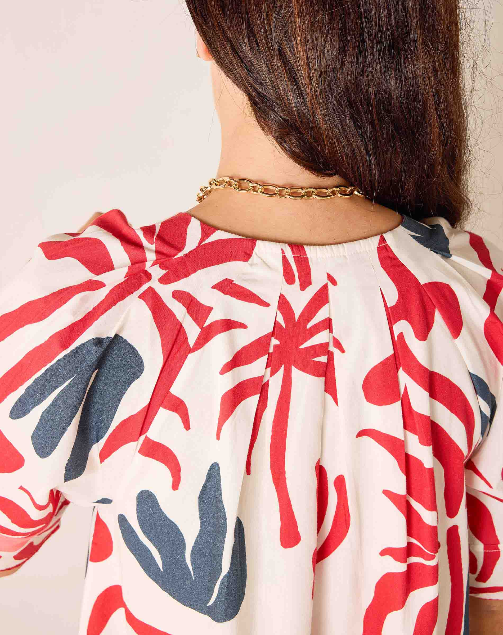 Person wearing a red and blue patterned garment with a neutral background