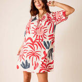 Woman wearing a colorful dress with abstract patterns on a plain background