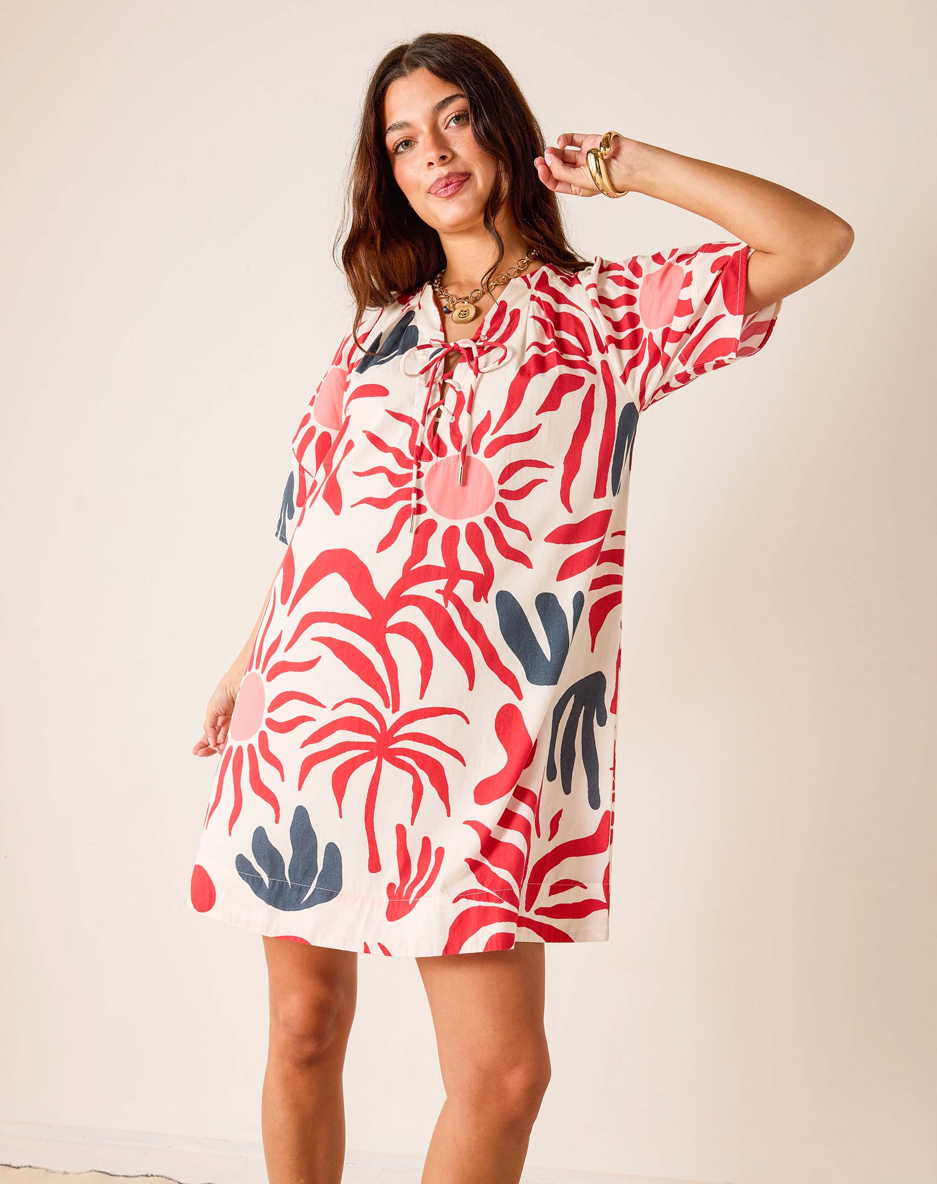 Woman wearing a colorful dress with abstract patterns on a plain background