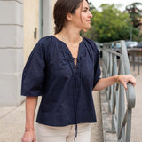 Woman wearing a navy blue blouse and beige pants standing outdoors.