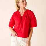 Woman wearing a red blouse with a beige background