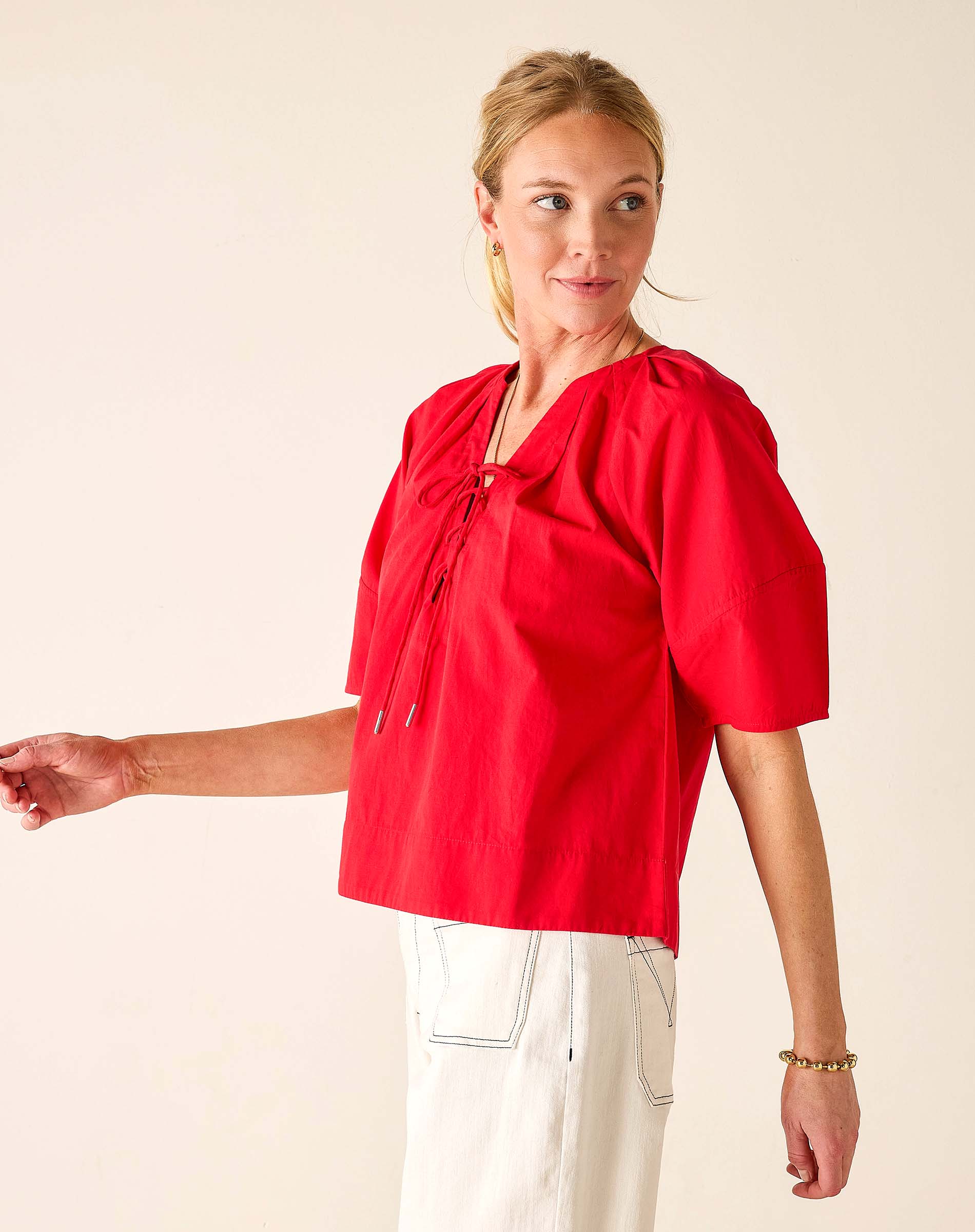 Woman wearing a red blouse with puff sleeves on a plain background