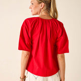 Woman wearing a red blouse with a plain background