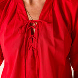 Red blouse with long sleeves and a tie detail on a neutral background