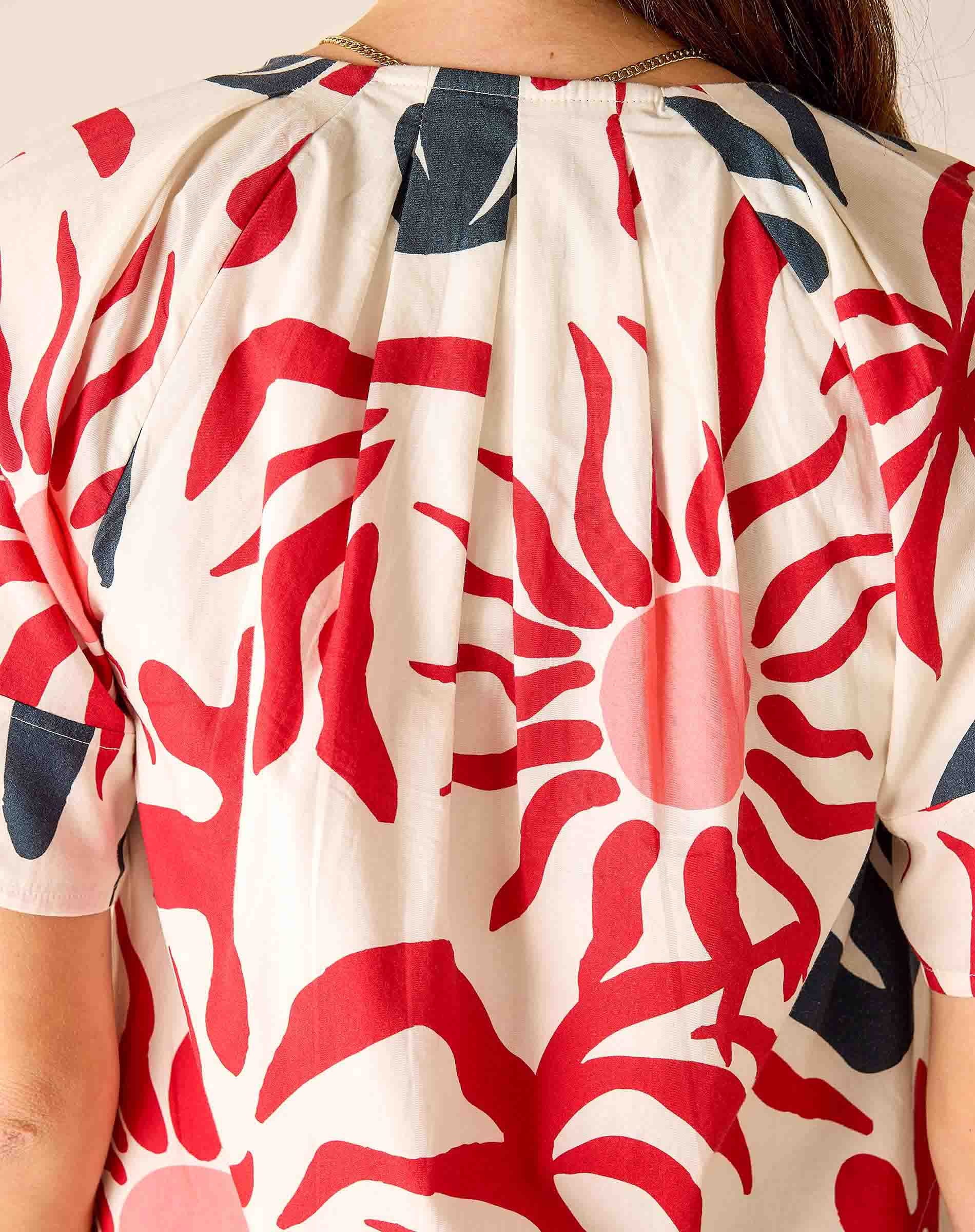 Close-up of a person wearing a patterned garment with red and blue designs on a beige background