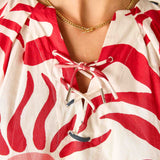 Red and white patterned top with a gold necklace