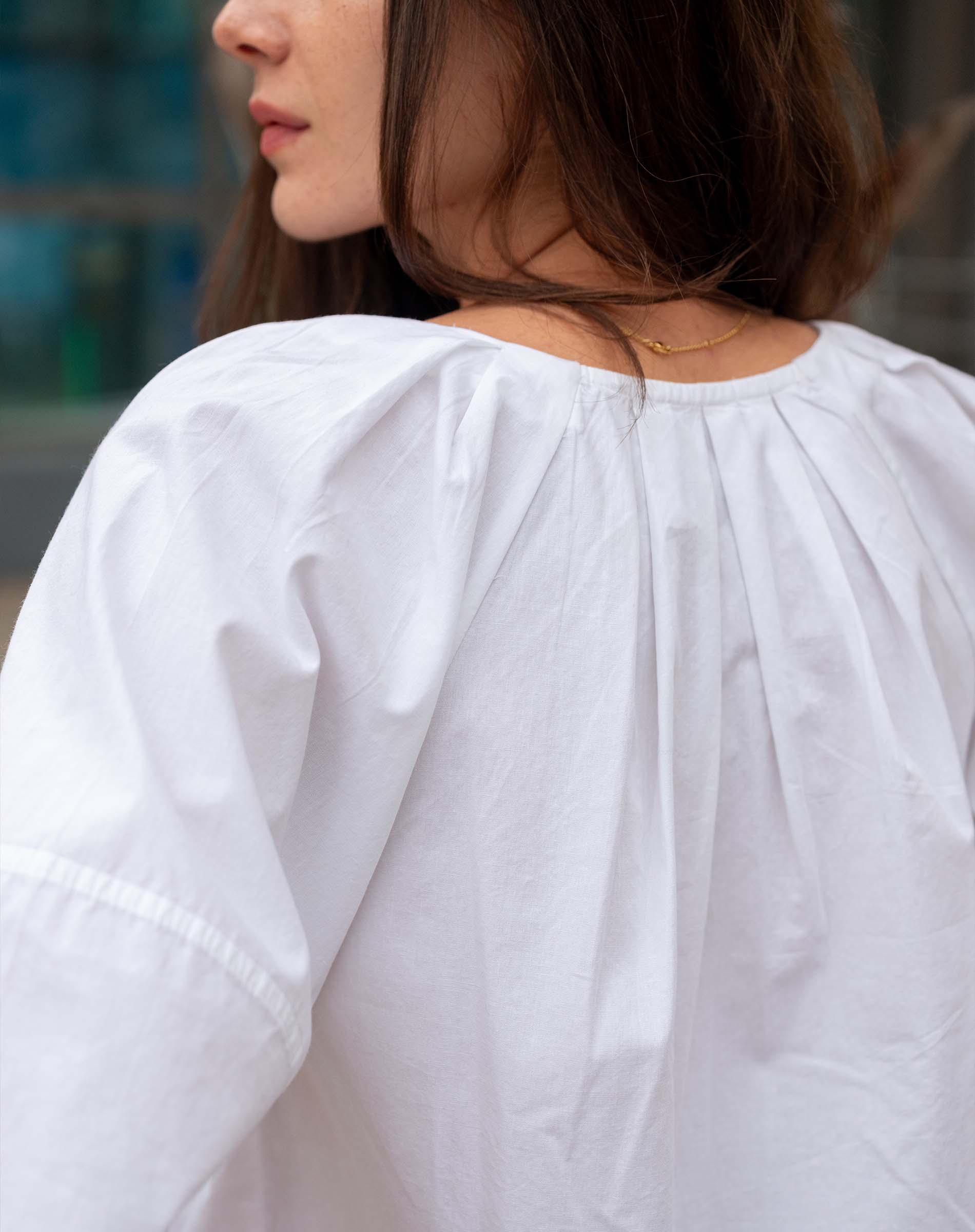 Person wearing a white blouse with puffed sleeves, blurred background