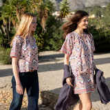 Multi-colored arched floral lacy top worn by models in a coastal setting.